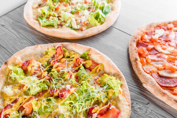 Assortment of pizza with meat, salami, prosciutto, tomatoes, dorblu cheese, mozzarella, parmesan, salad, spinach, red fish on wooden boards. Four cheese pizza, caesar, top view.