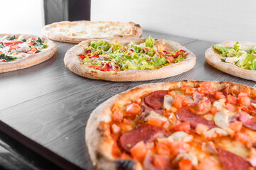 Assortment of pizza with meat, salami, prosciutto, tomatoes, dorblu cheese, mozzarella, parmesan, salad, spinach, red fish on wooden boards. Four cheese pizza, caesar, top view.