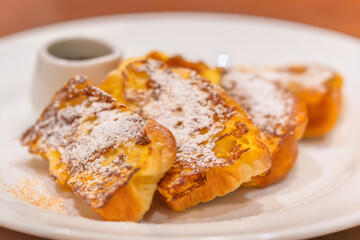 Close up on dish plate with french toasts also known as eggy bread made of sliced bread soaked in beaten eggs and milk then pan fried.