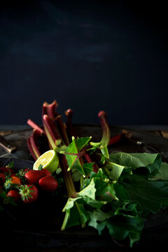 Studio shot of fresh rhubarb stalks, strawberries and halved lime
