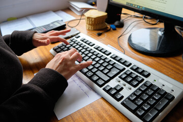 Hands typing on a computer keyboard.