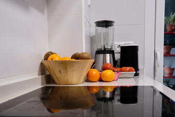 Composition in a kitchen with a fruit bowl with oranges, kiwis, tomatoes and various kitchen appliances