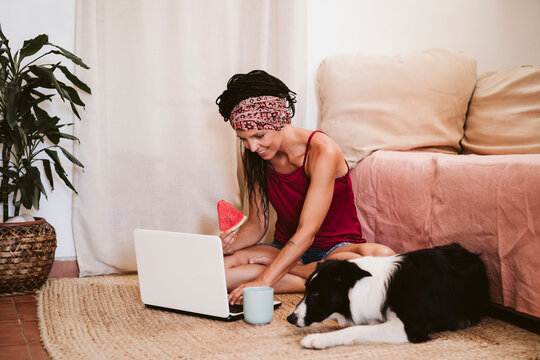Smiling woman using laptop while sitting by border collie dog at home