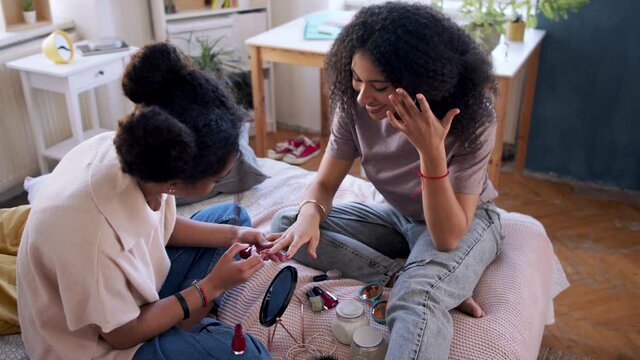 Portrait of young sisters indoors at home, painting nails.