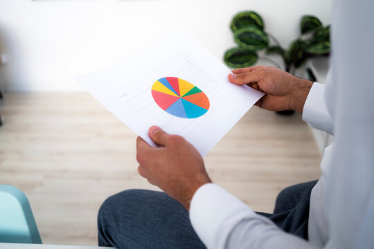 Male entrepreneur holding pie chart while working in office