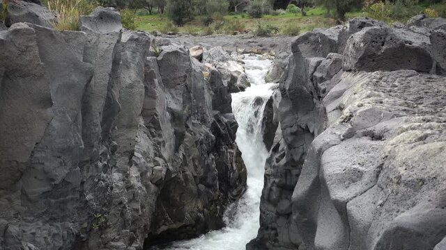 volcanic rock of Sicily nature split by a fault and smoothed by the waters flowing in a gorge of Simeto river 
