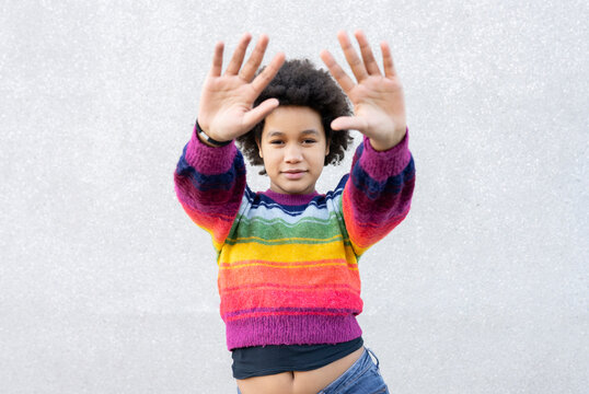 Girl With Hand Raised Standing Against Gray Wall