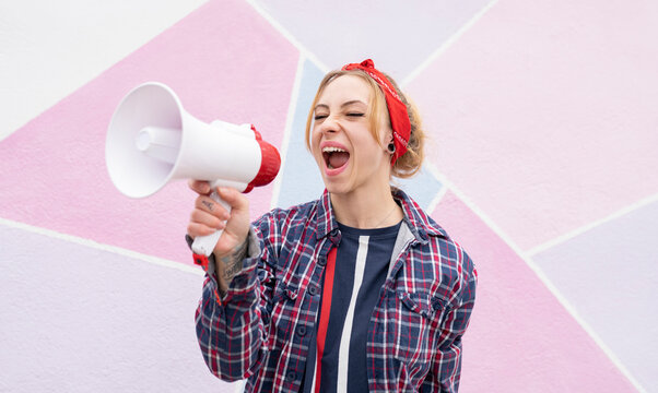 Woman screaming on megaphone while standing against wall