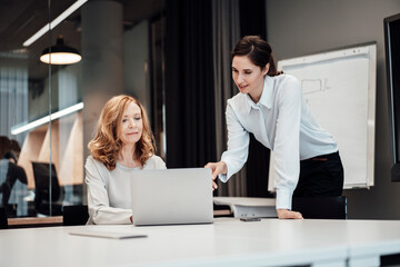 Businesswoman discussing over laptop while planning strategy during meeting at board room