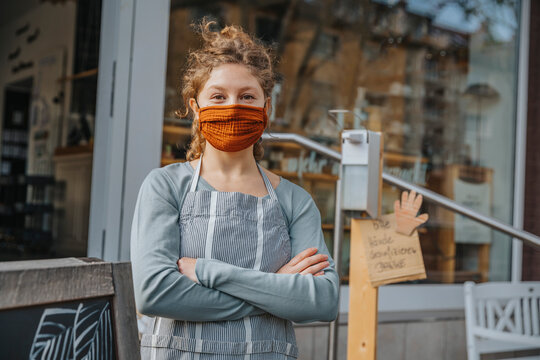 Young female entrepreneur with arms crossed against retail store