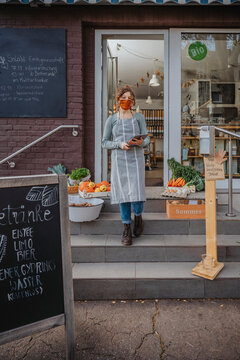 Female entrepreneur with digital tablet against organic shop during pandemic