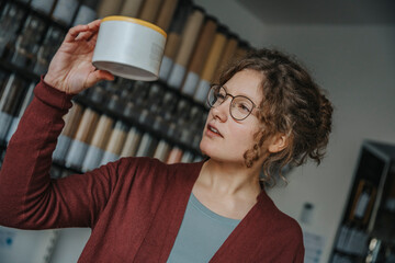 Young female customer reading label on product in retail store
