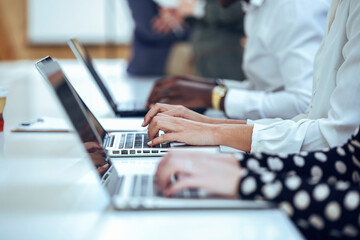 Business colleagues typing while using laptop at desk in coworking office