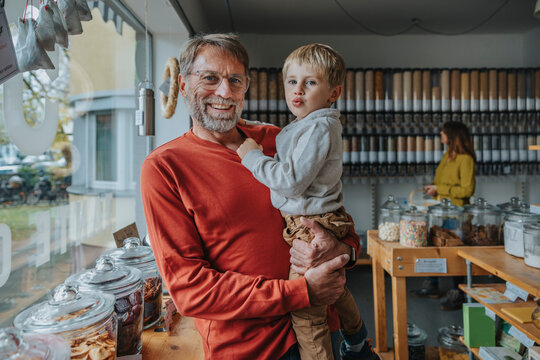 Mature father carrying son while standing in retail food store