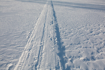 The trail from the snowmobile goes into the distance.