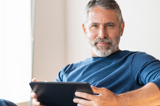 Confident businessman using digital tablet while sitting at home