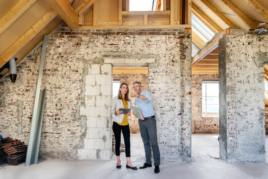 Architect explaining to businesswoman standing with digital tablet at construction site