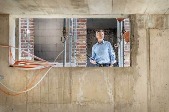 Thoughtful architect with digital tablet while standing at construction site