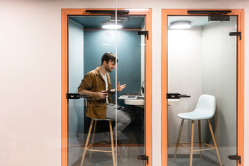 Smiling male entrepreneur on business video call through laptop in small cabin at work place