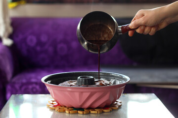 Pouring chocolate cream on the cake . close up view