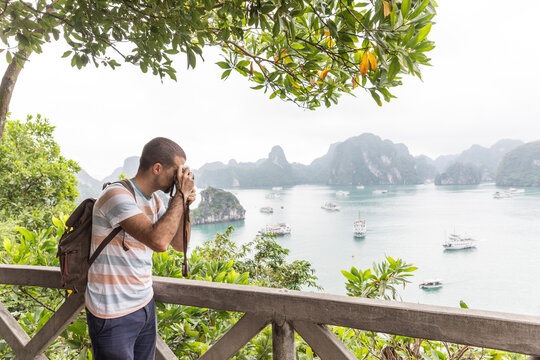 Male tourist with backpack photographing Halong bay at Vietnam