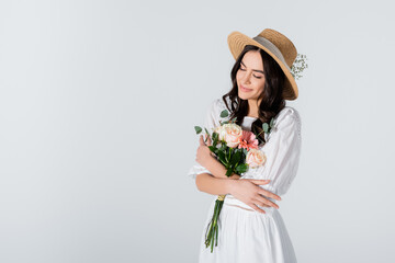 smiling woman in straw hat and dress holding bouquet of spring flowers isolated on white - Powered by Adobe