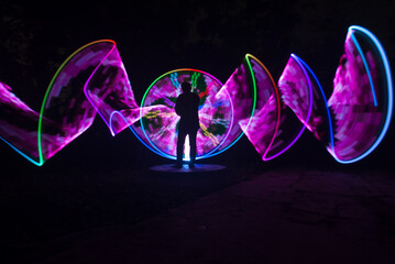 One person standing alone against a Colourful circle light painting as the backdrop