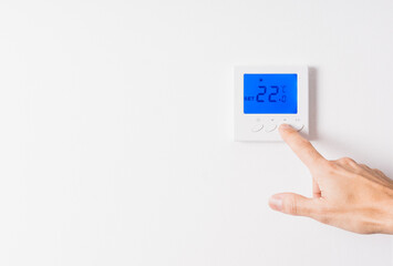 hand adjusting the temperature of a thermostat