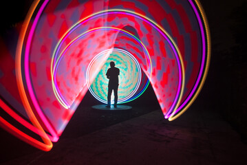 One person standing alone against a Colourful circle light painting as the backdrop