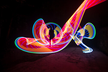 One person standing alone against a Colourful circle light painting as the backdrop