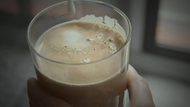 Close-up shot of woman making her favourite latte and finishing it with milk foam. Morning coffee is a good start of the day
