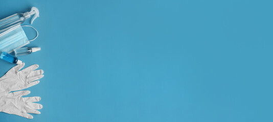 Medical gloves, mask and hand sanitizers on blue background, flat lay. Banner design with space for...