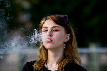 Vape teenager. Young pretty white caucasian girl with glasses on her head an electronic cigarette...