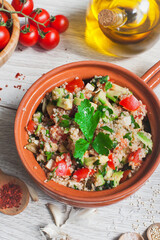 Delicious quinoa salad with avocado, cucumber and tomatoes on a rustic wooden table. Superfoods concept. Selective focus. View from above.