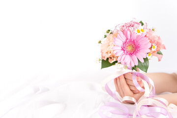 ピンクの花束を持つ子供の手　花のプレゼントイメージ素材