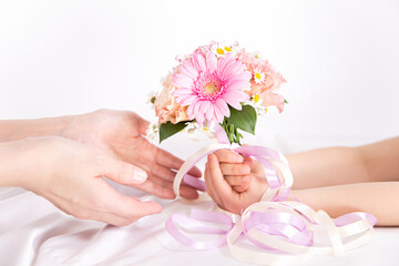 Obraz na płótnie Canvas ピンクの花束を渡す子供の手　花のプレゼントイメージ素材