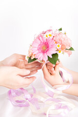 ピンクの花束を渡す子供の手　花のプレゼントイメージ素材