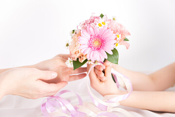 ピンクの花束を渡す子供の手　花のプレゼントイメージ素材