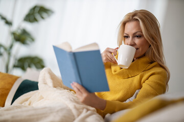 Young woman reading a book in bed
