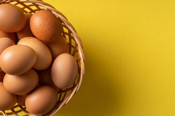 Top view on fresh organic eggs in basket on the yellow background