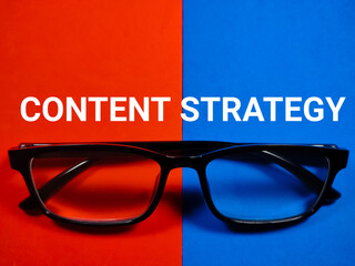 Eye glasses with text CONTENT STRATEGY on red and blue background.Business concept.