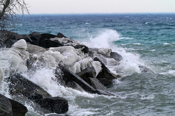 Big waves hitting rocky breakwall with much splashing and drama