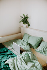 Laptop on an unfolded bed with linen linens. Conscious living concept, work from home, remote work, freelance, village life.