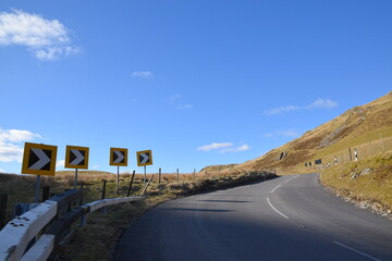 a sharp corner with warning signs on a welsh mountain road