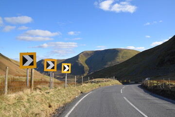 a sharp corner with warning signs on a welsh mountain road