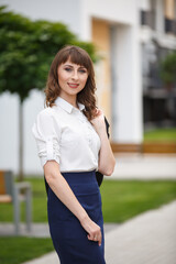 Young woman weared in classic business suit on background of a City park. Business style girl in...