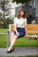 Young woman weared in classic business suit on background of a City park. Business style girl in...