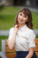 Young woman weared in classic business suit on background of a City park. Business style girl in...