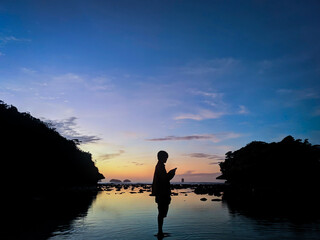 The silhouette of a person standing on the water