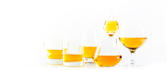 Hard strong alcoholic drinks and distillates in glasses and shot glass in assortment: vodka, cognac, tequila, scotch, brandy and whiskey, grappa, liqueur, vermouth, tincture, rum. White background